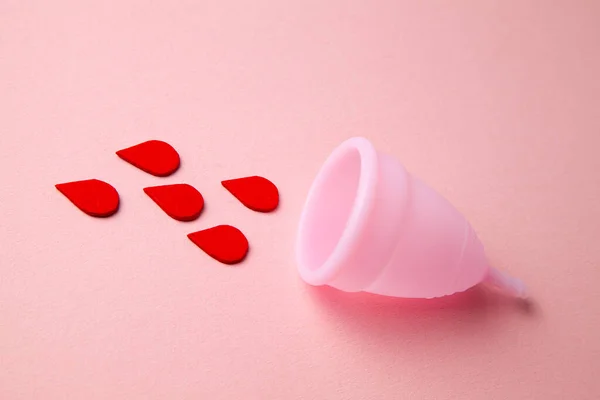 Copo menstrual de silicone. Saúde das mulheres e higiene alternativa. Copo com gotas de sangue em um fundo rosa . — Fotografia de Stock