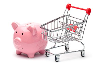 Pembe domuz kumbarası ve alışveriş arabası beyaz arka planda izole edilmiş. Mağazadan alışveriş yaparak tasarruf etme kavramı.