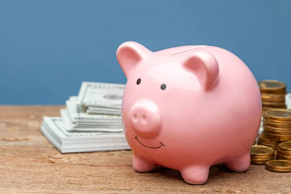 Banco y dinero con monedas y billetes de banco en una mesa de madera y fondo azul. — Foto de Stock