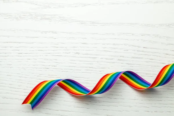 Cinta arco iris LGBT símbolo de la cinta de orgullo. Fondo de madera blanca. Copiar espacio para texto . — Foto de Stock