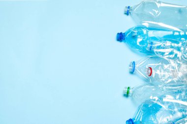 Mavi arka planda buruşmuş plastik şişeler. Plastik çöp. Metin için alanı kopyala.