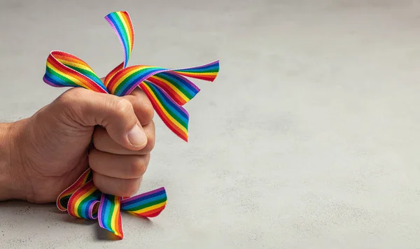 Homofobia. Basta de Orgullo LGBT. Hombre aprieta arcoíris LGBT cintas en su mano . — Foto de Stock