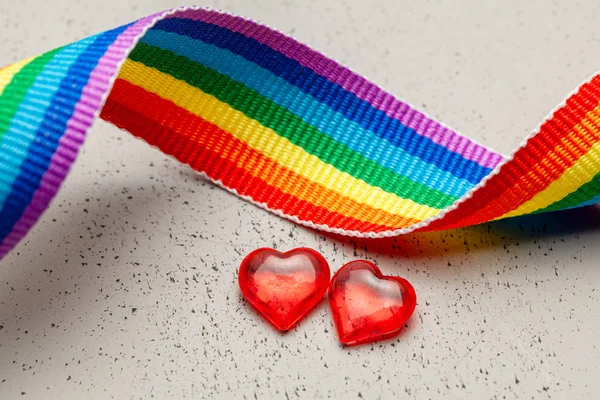 LGBT rainbow ribbon and two hearts. Pride tape symbol. Grey background