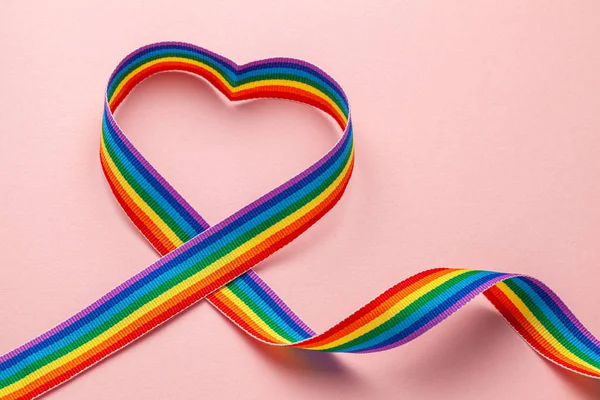 Cinta de arco iris LGBT en forma de corazón. Símbolo de cinta de orgullo. Fondo rosa — Foto de Stock