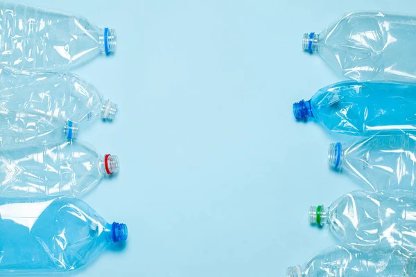 Gekromde plastic flessen op een blauwe achtergrond. Kunststof afval. Kopieer ruimte voor tekst. — Stockfoto