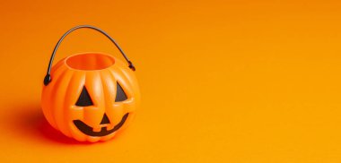 Cadılar Bayramı. Turuncu arka planda balkabağı şekeri sepeti.