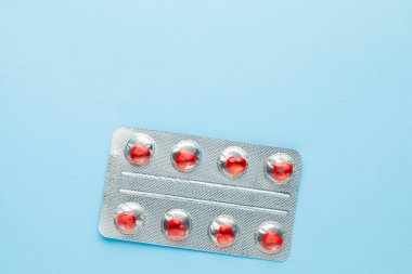 Aşk hapları. Kırmızı kalp şeklinde haplarla dolu su toplaması. Aşıklar için haplar ya da etki gücü. Mavi arka plan. Metin için alanı kopyala.