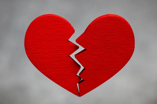 Gebroken hart. Scheuren in het rode hart, de relatie verbreken. Grijze achtergrond. — Stockfoto