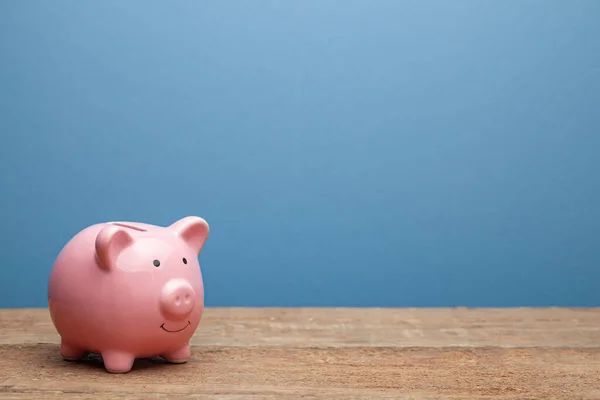 Hucha rosa sobre fondo azul. Copiar espacio para texto . —  Fotos de Stock