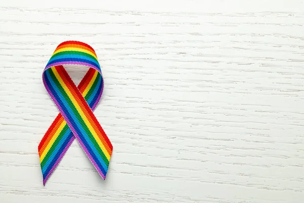 LGBT rainbow ribbon pride symbol. Stop homophobia. White wood background. Copy space for text.