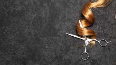 Kuaför. Siyah arka planda makas ve kıvırcık saç.