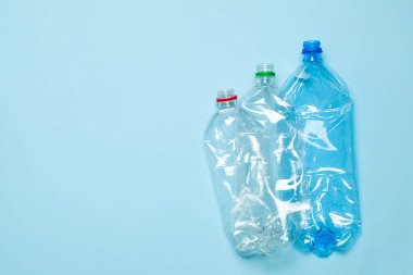 Mavi arka planda buruşmuş plastik şişeler. Plastik çöp. Metin için alanı kopyala.