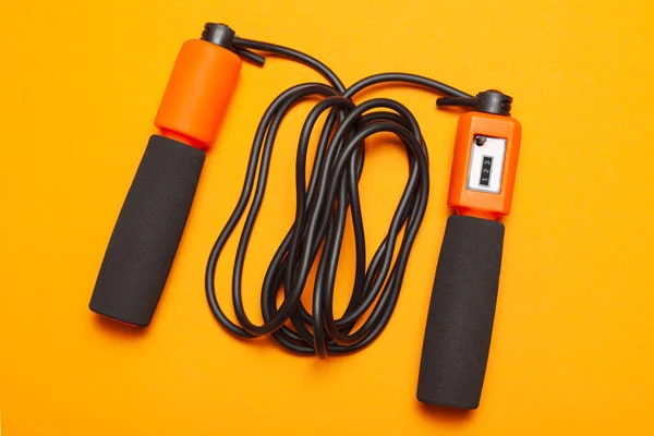 Hoppa rep. Roliga övningar för kroppens hälsa. Orange rep med hopprep med svart rep. Gul orange bakgrund — Stockfoto