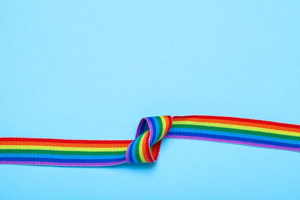 Fita com um nó. LGBT Orgulho Rainbow Ribbon contra fundo azul — Fotografia de Stock