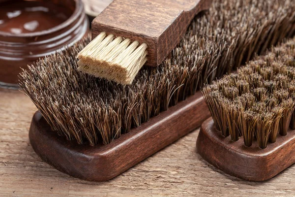 Brush for shoes. Cleaning and polishing shoes with brushes. Shoe polish and brush on wooden background