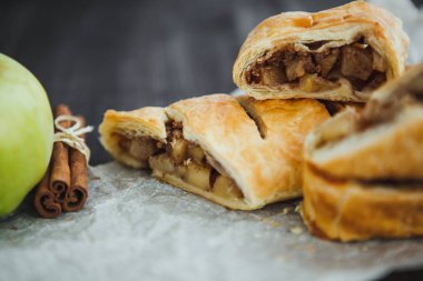 Parşömen üzerinde elmalı ve tarçınlı taze turta ve koyu arkaplan.