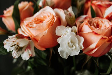 Siyah arka planda beyaz frezya tarzında beyaz frezya ile mercan renginde şakayık güllerinden oluşan büyük bir buket. karanlık aşk