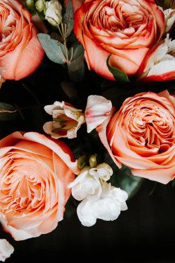Siyah arka planda beyaz frezya tarzında beyaz frezya ile mercan renginde şakayık güllerinden oluşan büyük bir buket. karanlık aşk