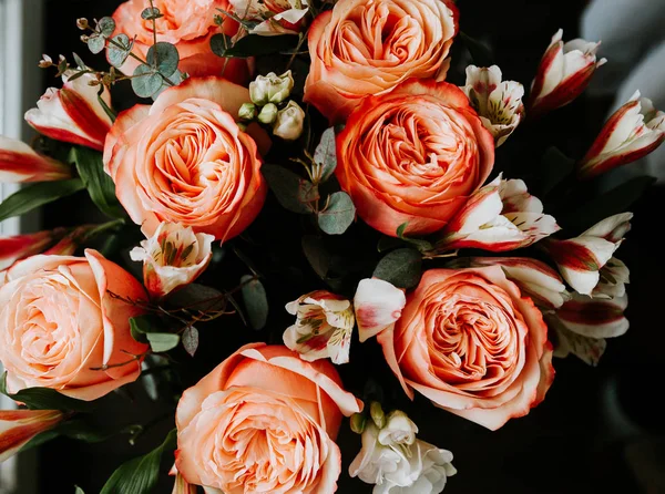 Siyah arka planda beyaz frezya tarzında beyaz frezya ile mercan renginde şakayık güllerinden oluşan büyük bir buket. karanlık aşk