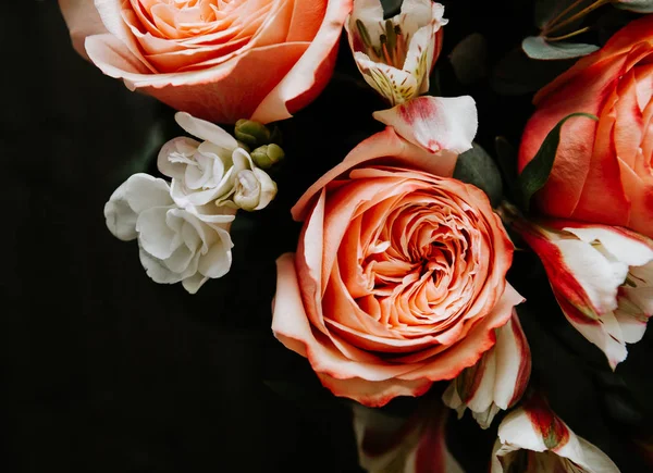 Siyah arka planda beyaz frezya tarzında beyaz frezya ile mercan renginde şakayık güllerinden oluşan büyük bir buket. karanlık aşk