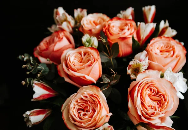 Siyah arka planda beyaz frezya tarzında beyaz frezya ile mercan renginde şakayık güllerinden oluşan büyük bir buket. karanlık aşk