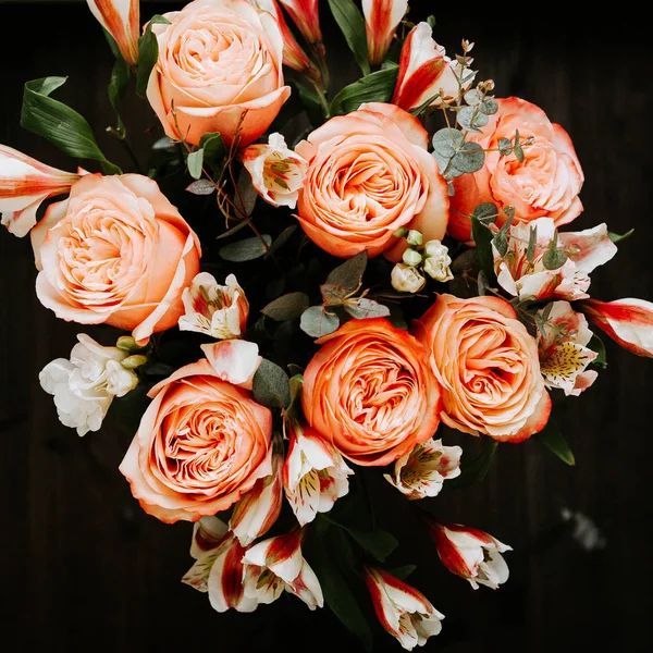 Siyah arka planda beyaz frezya tarzında beyaz frezya ile mercan renginde şakayık güllerinden oluşan büyük bir buket. karanlık aşk