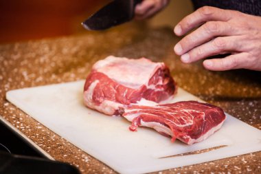 Adam biftek için et kesiyor.