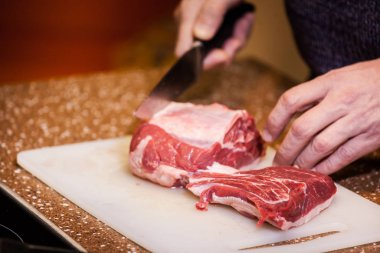 Adam biftek için et kesiyor.
