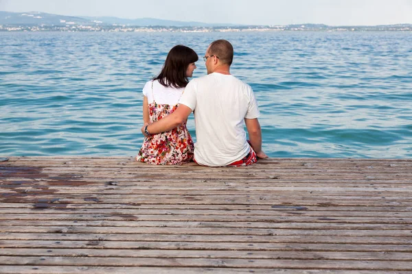 Couple d'amour assis sur une jetée surplombant la mer — Photo