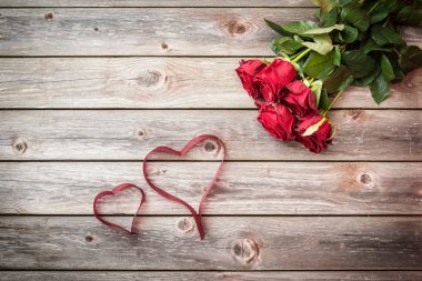 şerit üzerinden yürekleri ahşap arka plan üzerinde kırmızı gül buketi. Sevgiliye arka plan