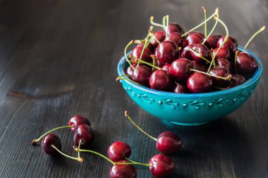 koyu arka plan üzerinde yeşil seramik kase kırmızı kiraz