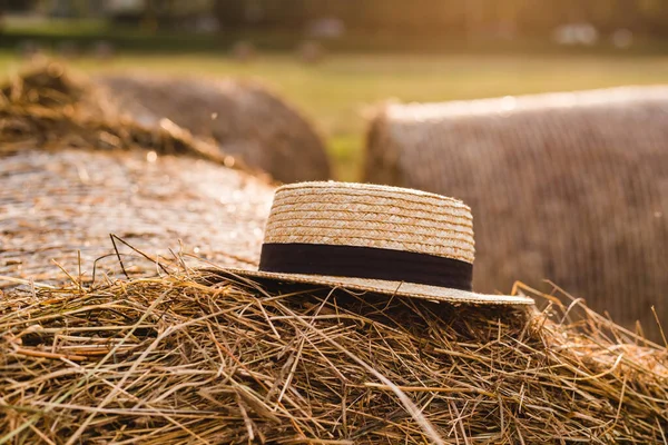 Foto paesaggio pagliaio rotola nel campo con cappello di paglia. Concetto di agricoltura rurale. Giorno d'estate, tramonto — Foto Stock