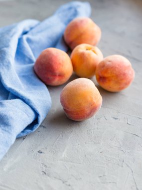 Taştan gri arka planda mavi pamuk bezli taze şeftaliler, yiyecek ve hasat kavramı. Kahvaltı, sağlıklı çiğ vejetaryen yiyecekler, bez bezi, branda dokusu..