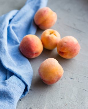 Taştan gri arka planda mavi pamuk bezli taze şeftaliler, yiyecek ve hasat kavramı. Kahvaltı, sağlıklı çiğ vejetaryen yiyecekler, bez bezi, branda dokusu..