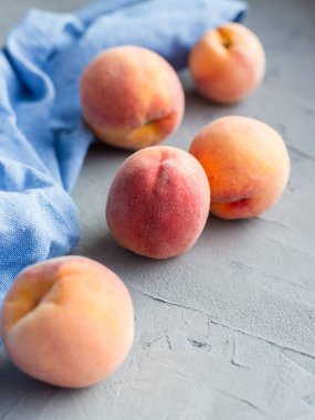Taştan gri arka planda mavi pamuk bezli taze şeftaliler, yiyecek ve hasat kavramı. Kahvaltı, sağlıklı çiğ vejetaryen yiyecekler, bez bezi, branda dokusu..