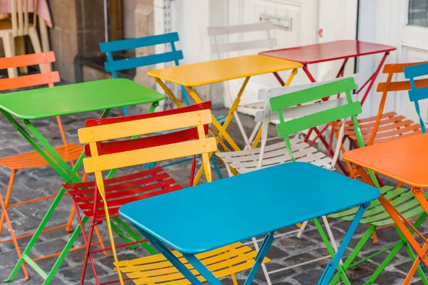 Street view van een koffie terras met kleurtafels en stoelen. Kleine cafetaria tafels op straat wachten op bezoekers — Stockfoto