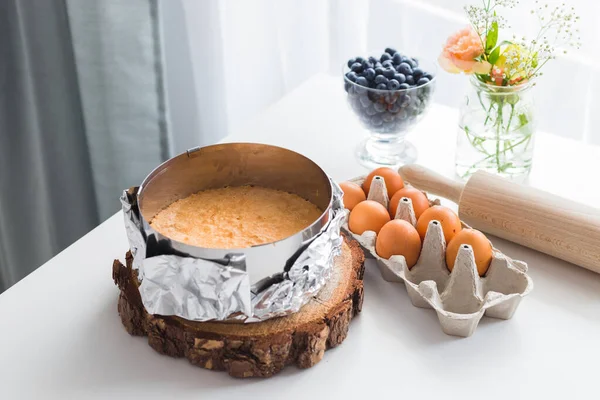 Домашний вкусный бисквит или мягкий торт с ингредиентами: яйца, ягоды, скалка на деревянном столе с копировальным местом. Концепция выпечки — стоковое фото