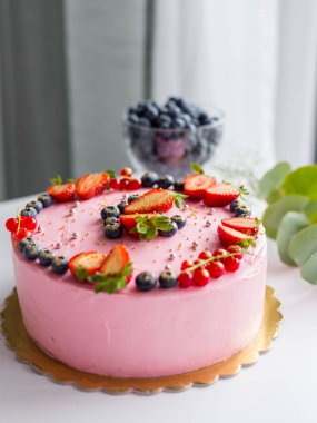 Çilek, yabanmersini ve frenk üzümü ile süslenmiş ev yapımı pembe doğum günü pastası. Yemek konsepti. Doğum günü krem peyniri pembe pasta