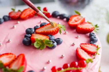 Pastayı fırçayla dekore eden şekerci. Doğum günü pastası. Altın çilek