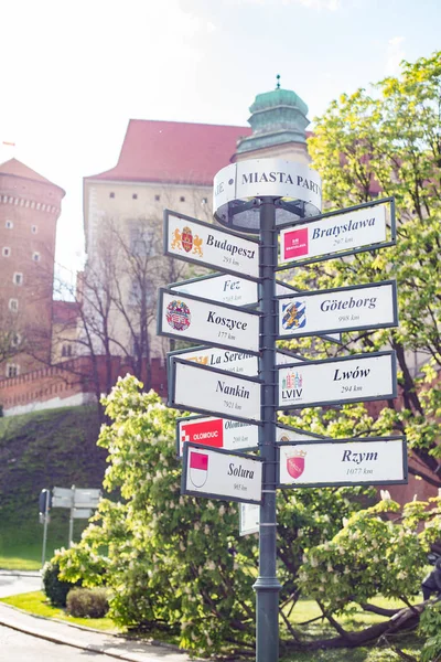 Cracóvia, POLÔNIA - 10 de maio de 2019: Direção para diferentes lugares do mundo indicados em um sinal de rua. Foto tirada na cidade da Polônia — Fotografia de Stock