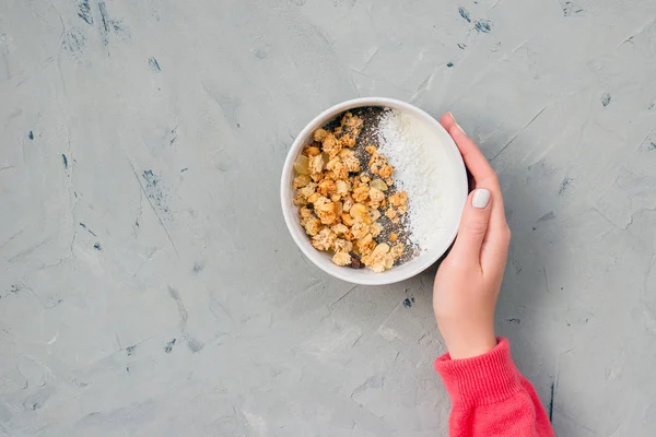 Чаша домашней мюсли с семенами йогурта и чиа на каменном фоне сверху. Пора завтракать. Молодая женщина ест мюсли в белой тарелке — стоковое фото