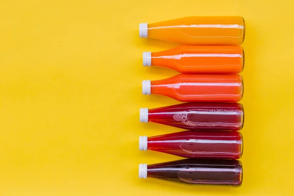 Juice Bottle Mock-Up, gradient juice bottles on yellow background. Variety of colorful Smoothies, top view. Healthy Food concept