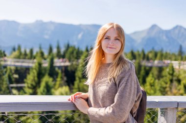 Sırt çantalı genç bir kadın uçurumun kenarında duruyor. Seyahat ve turizm konsepti. Copyspace Dağların arka planında duran kızıl saçlı genç bir kadın