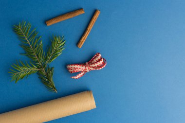 Köknar ağacı dalı, tarçın ve ambalaj kağıdıyla mavi Noel arkaplanı. Hediye paketleme konsepti. Yılın rengi.