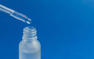 Mavi modaya uygun arka planda pipetli kozmetik şişesi. Bilim ya da tıbbi test konsepti. 2020 Yılı Rengi