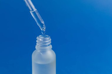 Mavi modaya uygun arka planda pipetli kozmetik şişesi. Bilim ya da tıbbi test konsepti. 2020 Yılı Rengi