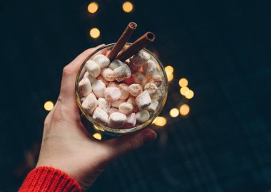 Kadın eli, elinde tarçınlı ve lokum kaplı bir fincan sıcak kakao tutuyor. Noel ve yeni yıl geçmişi. Üst görünüm