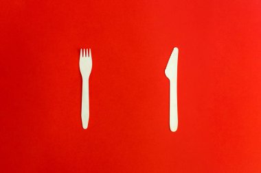 Kırmızı arka planda tek kullanımlık ahşap çatal ve bıçak geri dönüşüm ve çevre dostu kavram. Sıfır atık, plastiksiz eşyalar, plastiği durdur. Üst Manzara. Mesaj için yer. Çam ağacından yapılmış çatal bıçak takımı..