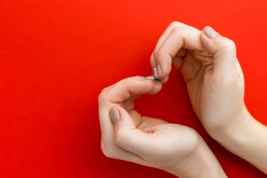 Kırmızı arka planda kalp şekillendiren kadının elleri, aşk konsepti, üst görünüm