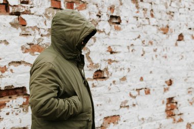 Başında kapüşonlu bir adam, yüzü görünmüyor. Uyuşturucu, hırsızlık ve suç kavramı. Beyaz Retro Grunge Tuğla Duvarlı Kırmızı Arkaplan